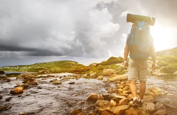 Wanderer überquert mit Rucksack einen Fluss. — Stockfoto