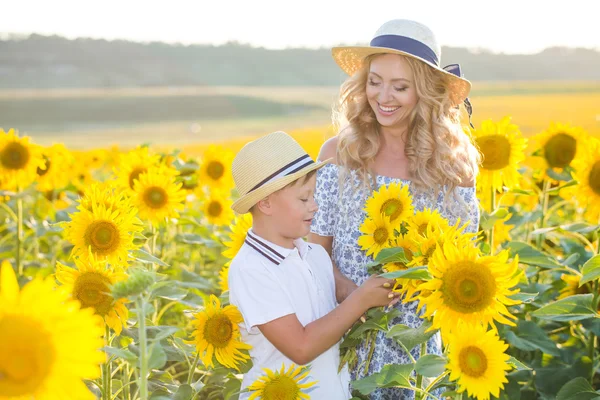 Schöne Frau mit Sohn im Sonnenblumenfeld — Stockfoto