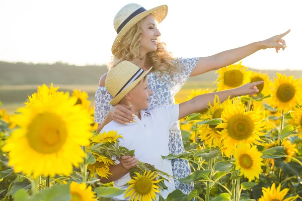 Mooie vrouw met zoon in zonnebloem veld — Stockfoto