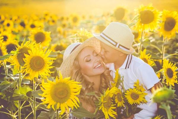 Vacker kvinna med son i solros fält — Stockfoto