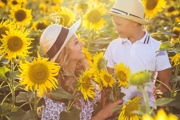 Mooie vrouw met zoon in zonnebloem veld — Stockfoto