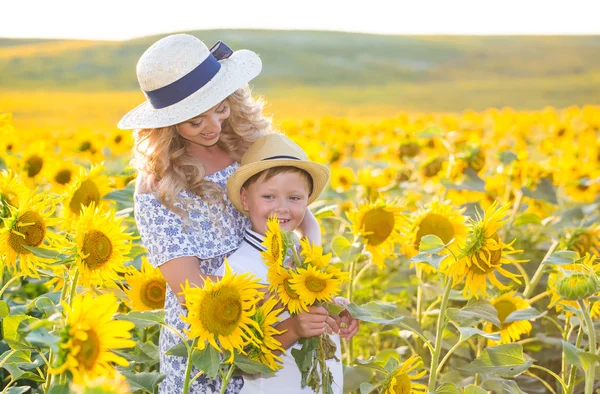 Mulher bonita com filho no campo de girassol — Fotografia de Stock