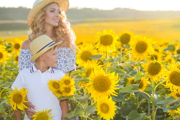 Красива жінка з сином на соняшниковому полі — стокове фото
