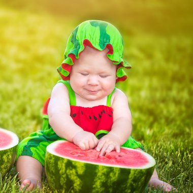 Küçük çocuk çimlere oturup karpuz ile