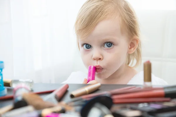 Niedliches kleines Mädchen mit Kosmetik und Spiegel. — Stockfoto