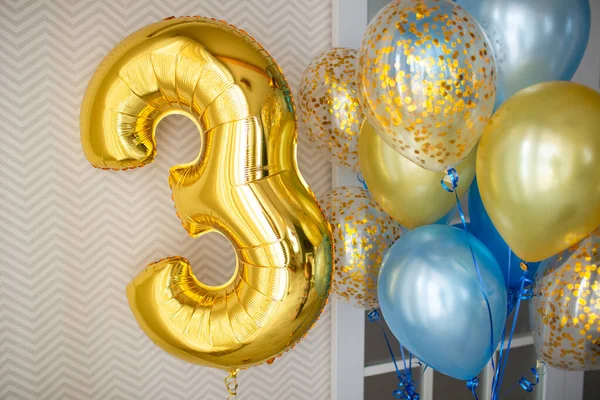 在婴儿三周岁生日的时候 用蓝色透明的气球装饰一个灯具室 上面装饰着金冠 气球束和带锯齿形壁纸背景上的3号气球 — 图库照片