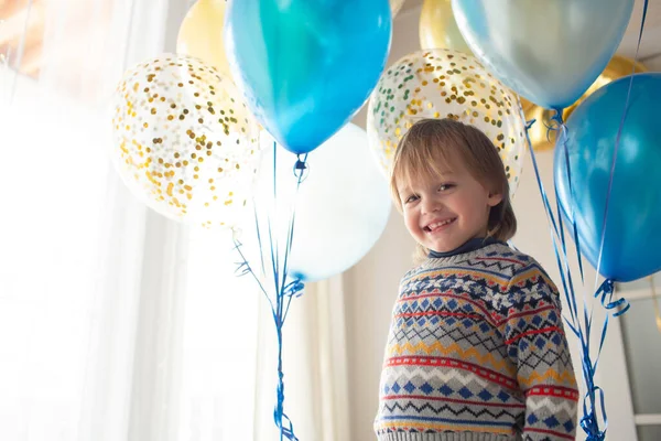 赤ちゃんの3歳の誕生日プレゼント パターンの美しいセーターの小さな男の子は風船を持っています 北欧風の大きな窓の明るいインテリア — ストック写真