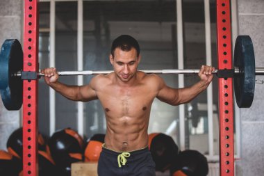 Çıplak gövdeli bir sporcunun fotoğrafı. Atletik adam çeşitli egzersizler yapıyor.