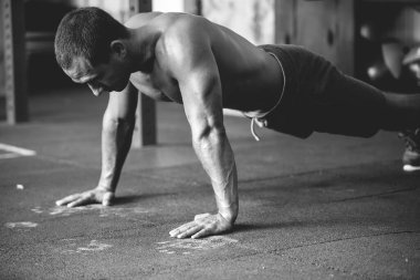 Çıplak gövdeli bir sporcunun siyah beyaz pozu. Atletik adam çeşitli egzersizler yapıyor.