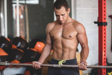 Çıplak gövdeli bir sporcunun fotoğrafı. Atletik adam çeşitli egzersizler yapıyor.