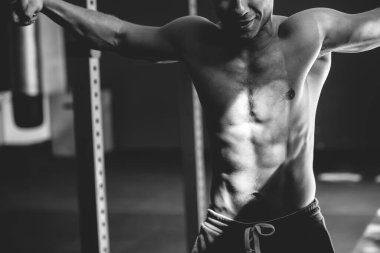 Çıplak gövdeli bir sporcunun siyah beyaz pozu. Atletik adam çeşitli egzersizler yapıyor.