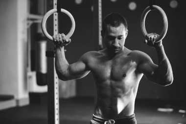 Çıplak gövdeli bir sporcunun siyah beyaz pozu. Atletik adam çeşitli egzersizler yapıyor.