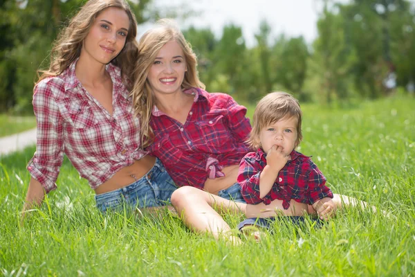 Meninas bonitas com menino na grama — Fotografia de Stock