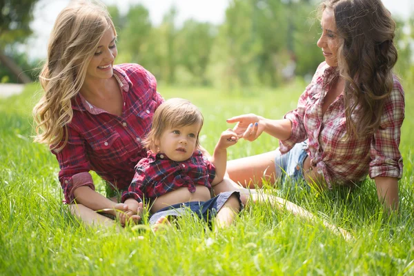 Meninas bonitas com menino na grama — Fotografia de Stock