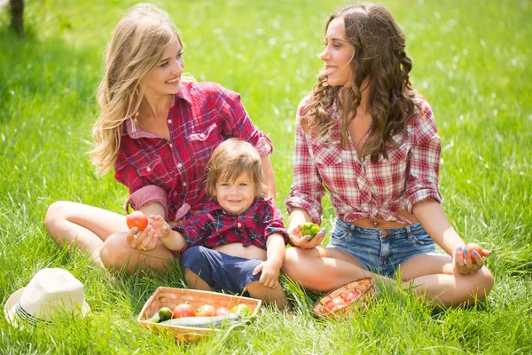 Meninas bonitas com menino na grama — Fotografia de Stock