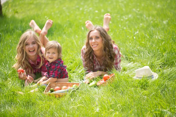 Beautiful girls with little boy on the grass — Stock Photo, Image