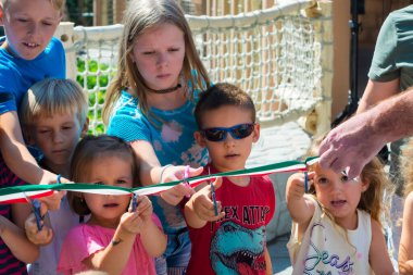 SZEGED, HUNGARY - 30 Ağustos. 2020: Çocuklar, Szeged Zoo 'daki Hint gergedan sergisinin açılış töreninde kaseti kesiyorlar