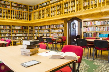 Eski bir kütüphanenin iç tasarımı, masaları ve kitap rafları olan salon.