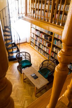 Eğri merdivenleri ve sandalyeleri olan eski bir kütüphanenin iç tasarımı.
