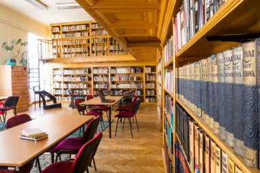 Eski bir kütüphanenin iç tasarımı, masaları ve kitap rafları olan salon.