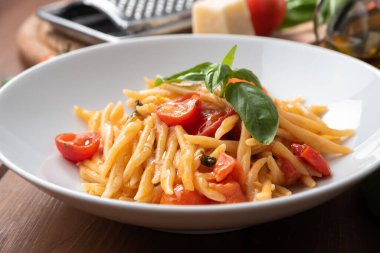 Bir tabak lezzetli trofie makarna, fesleğenli ve kiraz domatesli, İtalyan yemeği. 