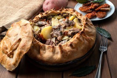 Sardinian Panada, a traditional savory pie stuffed with lamb, potatoes and dried tomato  clipart