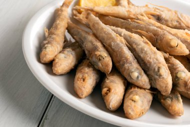 Limon dilimleriyle servis edilen bir tabak kızarmış balık..