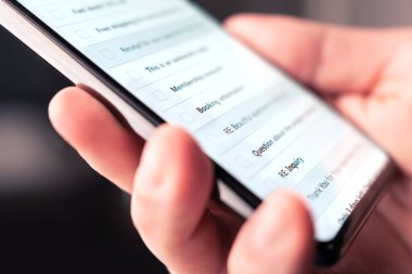 Cep telefonundaki e-posta kutusunda yeni okunmamış mesajlar, pazarlama bültenleri ve spam var. Akıllı telefondan dijital posta hesabına bakan biri. İş adamı cep telefonuyla iş iletilerini okuyor..