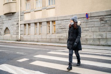 Kışın karşıdan karşıya geçen yayalar. Şehirde yaya geçidinde bir kadın, zebra geçidi. Ceket ya da ceket..
