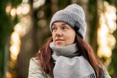 Ormanda pozitif bir kadın. Finlandiya 'da kış ya da bahar doğası. Gri bereli ve eşarplı mutlu insan. Gülümseyen tatlı kız. Açık havada rahat moda yaşam tarzı.