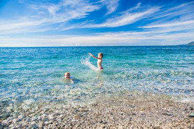 Erkek ve kız sahilde gülümseyen, denizde yüzmek