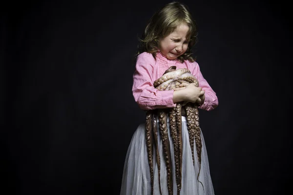 Chorando menina em uma blusa rosa e saia branca no fundo preto texturizado com as mãos de polvo — Fotografia de Stock