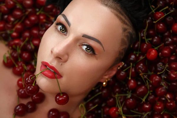 Girl bodybuilder on the background of ripe red cherries — Stock Photo, Image