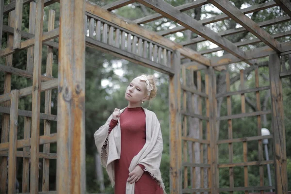 Beautiful young blonde girl in a red mini-dress in the park — Stock Photo, Image