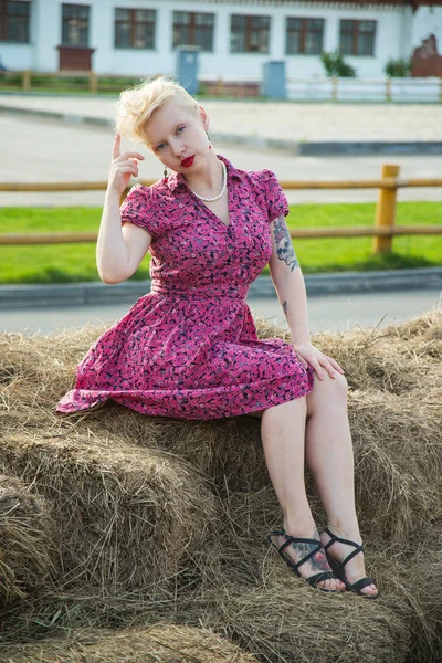 Красива блондинка в стилі пін-ап в яскравій сукні на сіні — стокове фото
