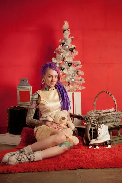 Foto de Natal de uma menina com dreadlocks roxos e tatuagens no estúdio — Fotografia de Stock