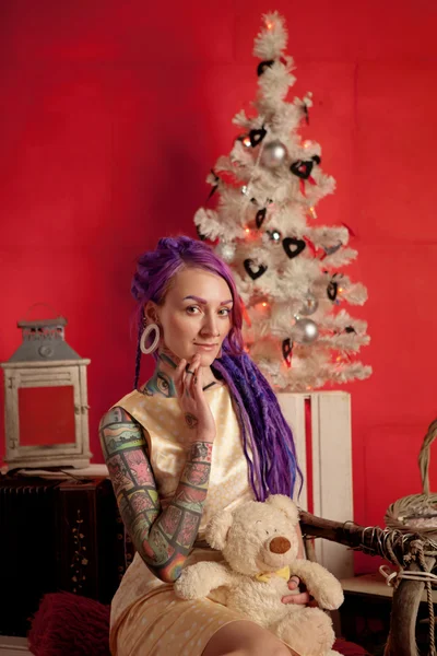 Foto de Natal de uma menina com dreadlocks roxos e tatuagens no estúdio — Fotografia de Stock