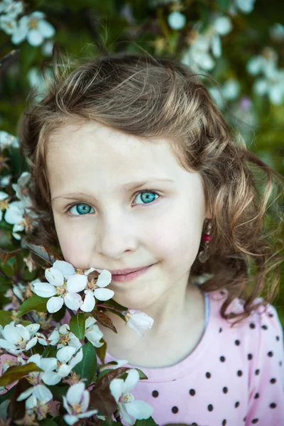 Linda loira menina de olhos azuis em um pomar de maçã florido — Fotografia de Stock