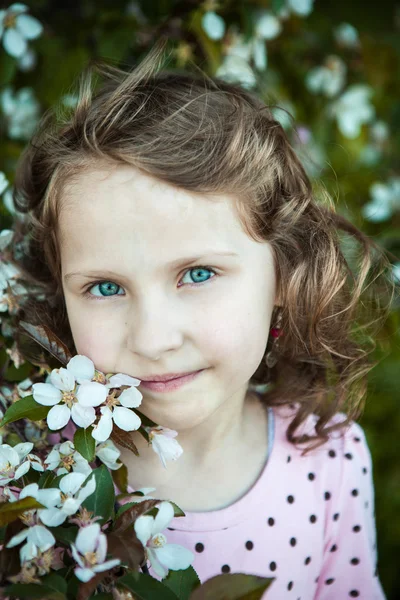 Linda loira menina de olhos azuis em um pomar de maçã florido — Fotografia de Stock
