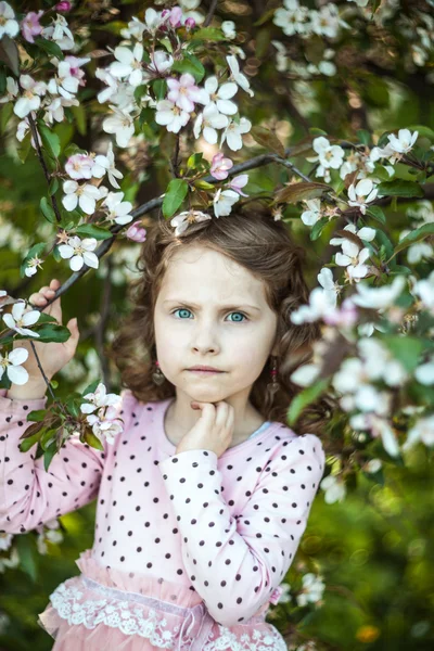 Prachtige blond blauwogige meisje in een bloeiende appelboomgaard — Stockfoto