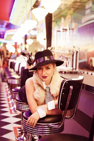 Young beautiful girl in the hat, lying on a chair at a bar rack