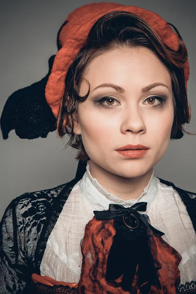 Young beautiful dark-haired woman in a felt hat, long black skirt and red corset — Stock Photo, Image