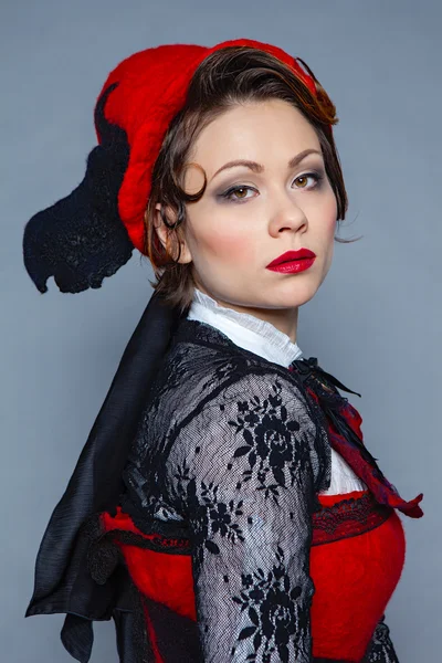 Молодая красивая темноволосая женщина в войлочной шляпе, длинной черной юбке и красном корсете — стоковое фото