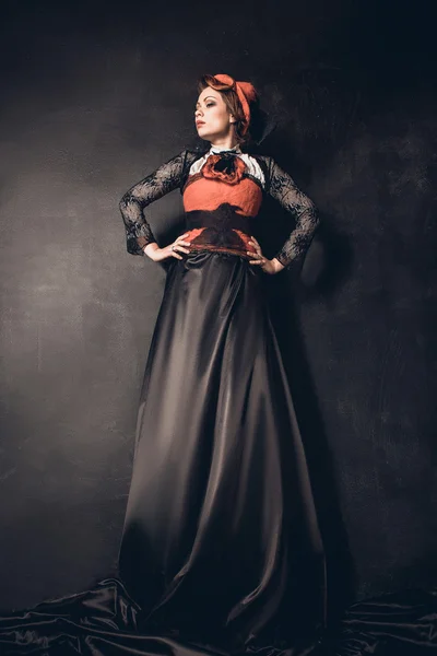 Junge schöne dunkelhaarige Frau mit Filzhut, langem schwarzen Rock und rotem Korsett — Stockfoto