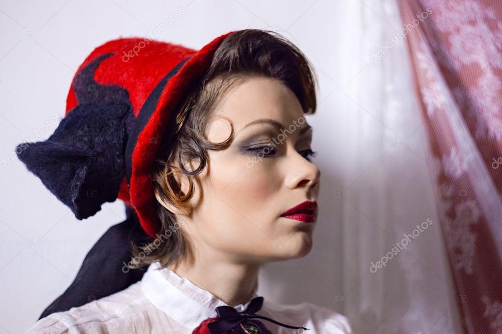 Young beautiful dark-haired woman in a felt hat, long black skirt and red corset