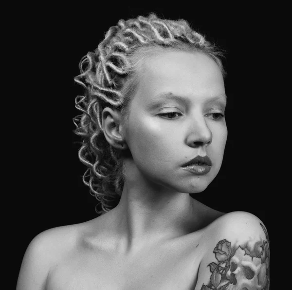 Mooie jonge blonde vrouw met dunne krullend dreadlocks en een tatoeage op haar onderarm — Stockfoto