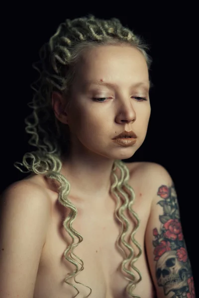 Mooie jonge blonde vrouw met dunne krullend dreadlocks en een tatoeage op haar onderarm — Stockfoto