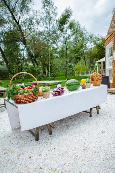 Fruits and vegetables in a basket, standing on a table covered with a white cloth — Stock Photo, Image