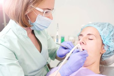 Dentist doctor treats teeth of a young girl. Dental office background.