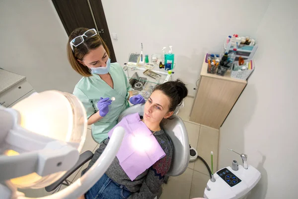 歯医者は歯の椅子で患者を検査します — ストック写真
